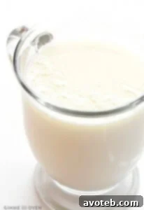 A beautifully presented mug of homemade white hot chocolate on a wooden surface, garnished with creamy whipped topping and a hint of a cozy atmosphere.