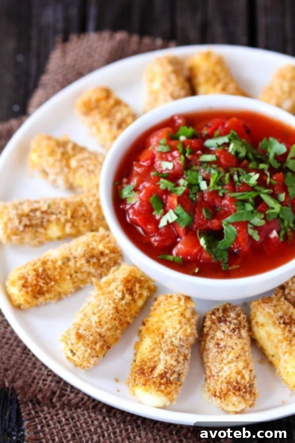 A close-up shot of crispy Baked Mexican Mozzarella Cheese Sticks piled high, ready to be dipped.