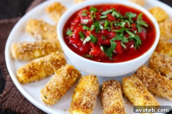 A hand reaching for a crispy Baked Mexican Mozzarella Cheese Stick, showcasing the cheesy pull.