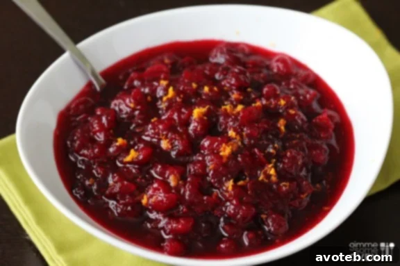 Lush Orange Bourbon Cranberry Sauce with orange slices and rosemary sprigs, ready for serving.