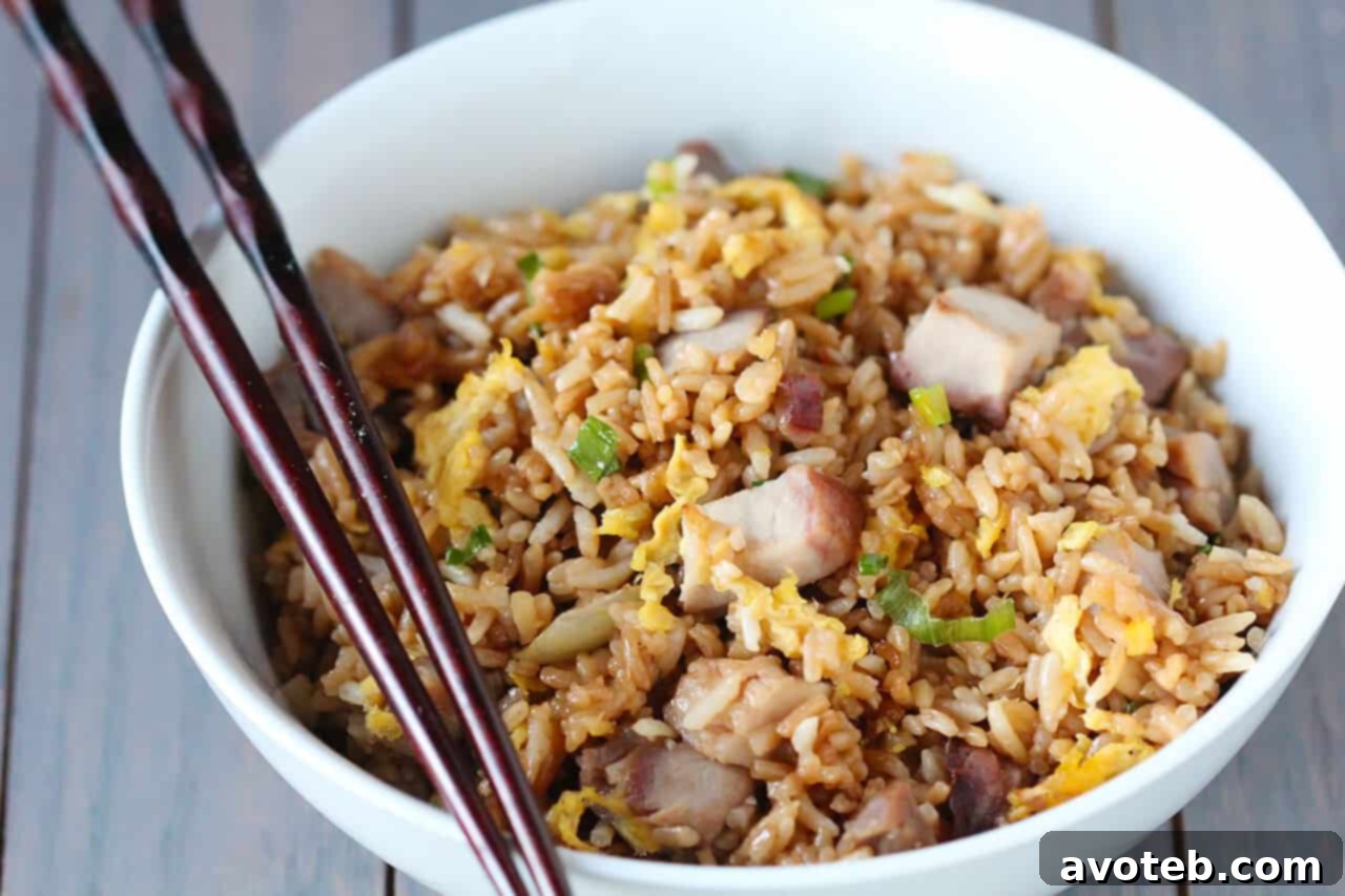 A close-up shot of homemade Pork Fried Rice, garnished with fresh green onions.