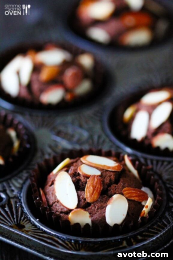 A close-up shot of a baked Chocolate Almond Muffin, showcasing its fluffy texture and golden-brown top sprinkled with almonds.