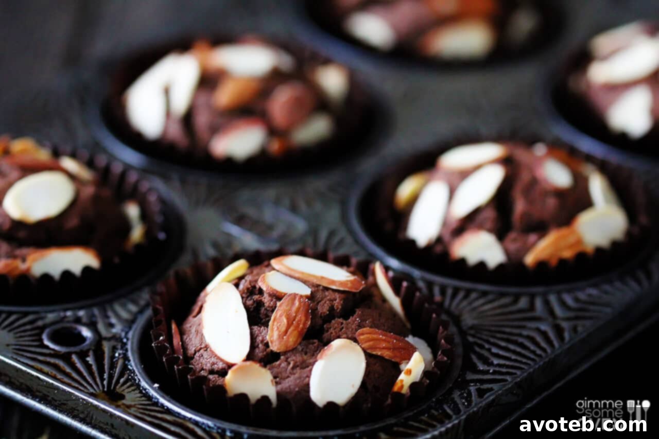 Close-up of fluffy Chocolate Almond Muffins with a sprinkle of sliced almonds on top.