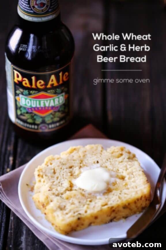 A close-up shot of a sliced Whole Wheat Garlic & Herb Beer Bread loaf, showing the fluffy interior and herbs.
