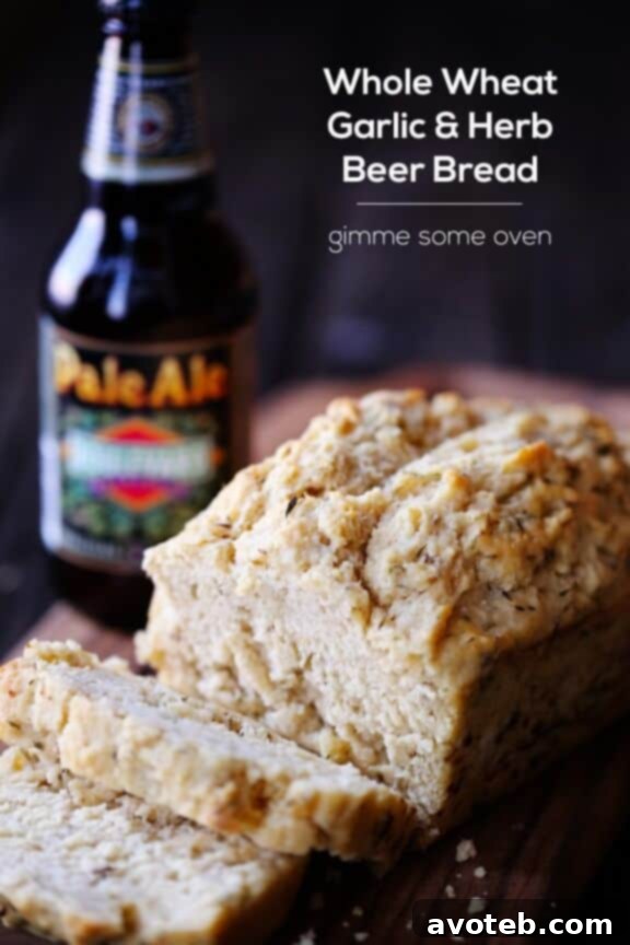 A freshly baked loaf of Whole Wheat Garlic & Herb Beer Bread resting in its loaf pan.