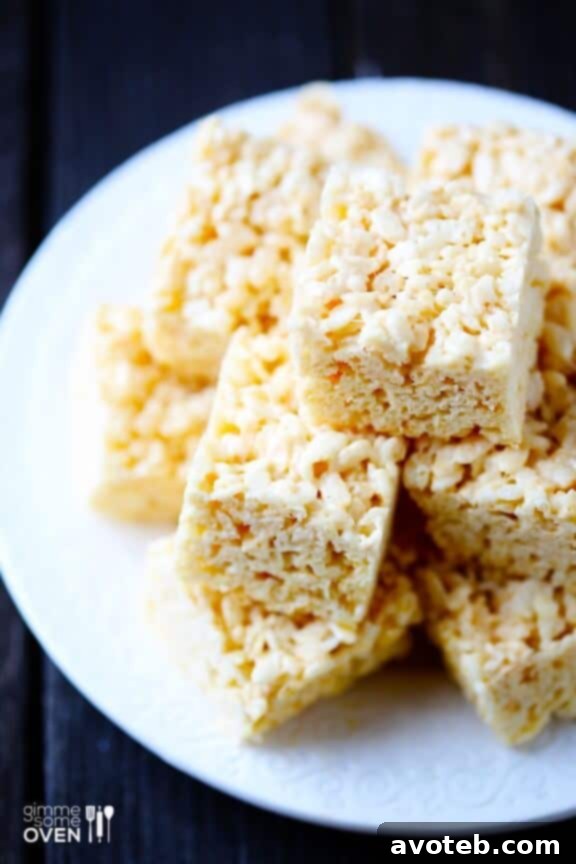 A close up shot of a stack of homemade Coconut Oil Rice Krispie Treats on a rustic wooden board, ready for a sweet treat.
