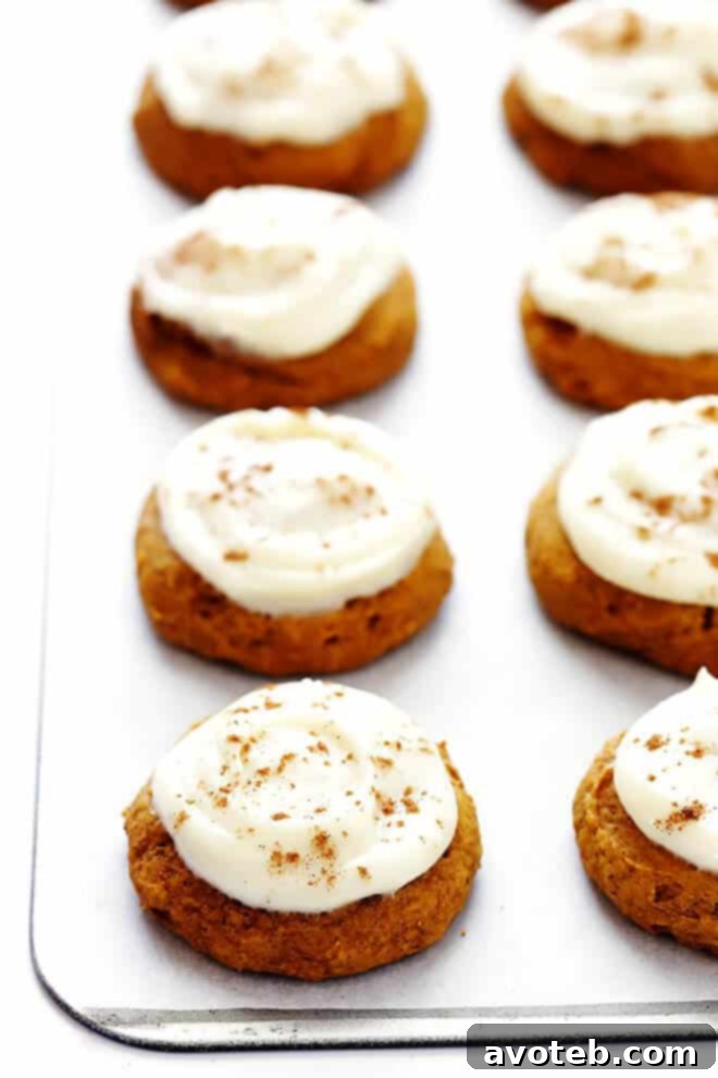 A plate of perfectly soft pumpkin cookies generously iced with creamy, white cream cheese frosting, ready for fall enjoyment.