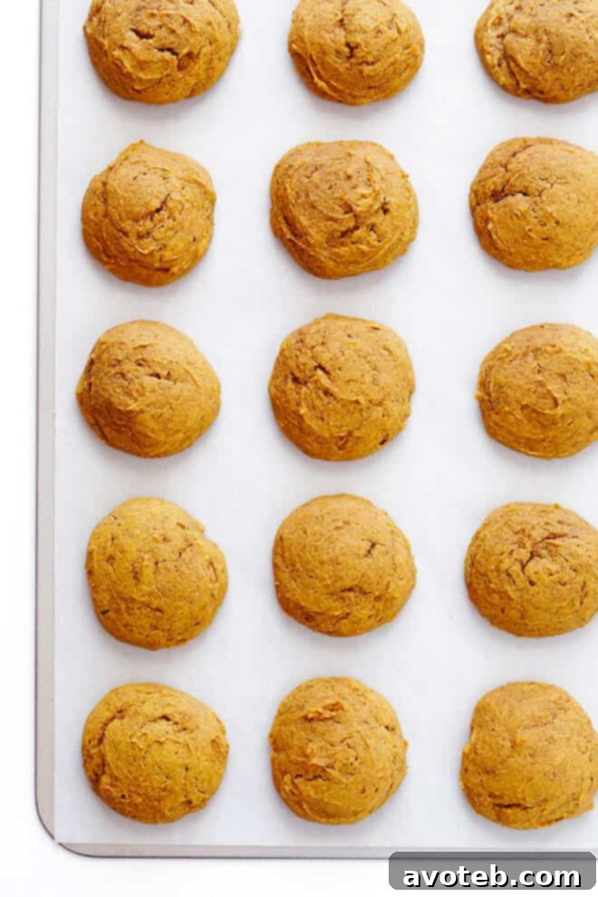 Close-up shot of several soft pumpkin cookies generously covered with smooth cream cheese frosting, showcasing their inviting texture.