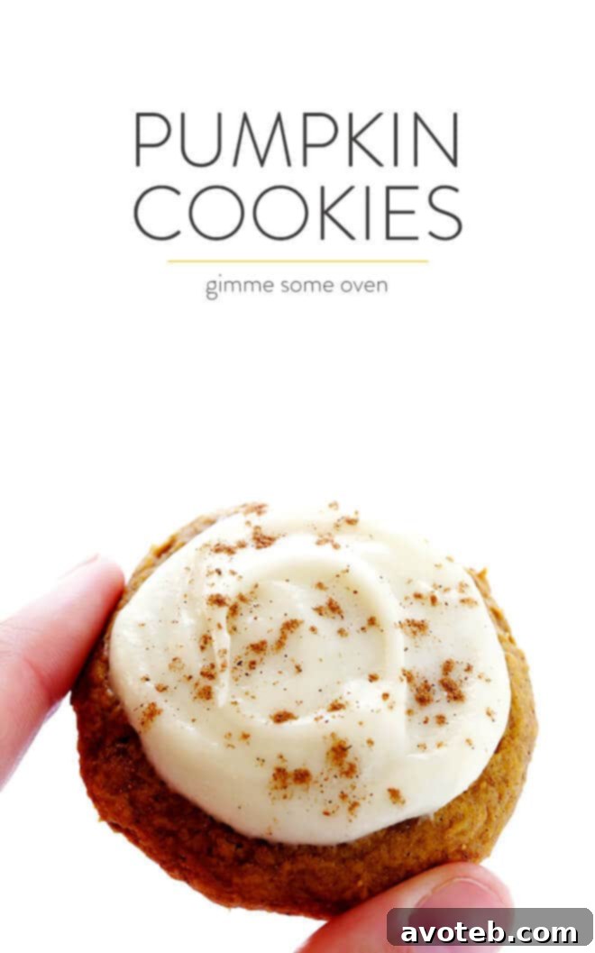 A large pile of freshly baked soft pumpkin cookies, some frosted with cream cheese, on a white tray, signifying abundance and deliciousness.