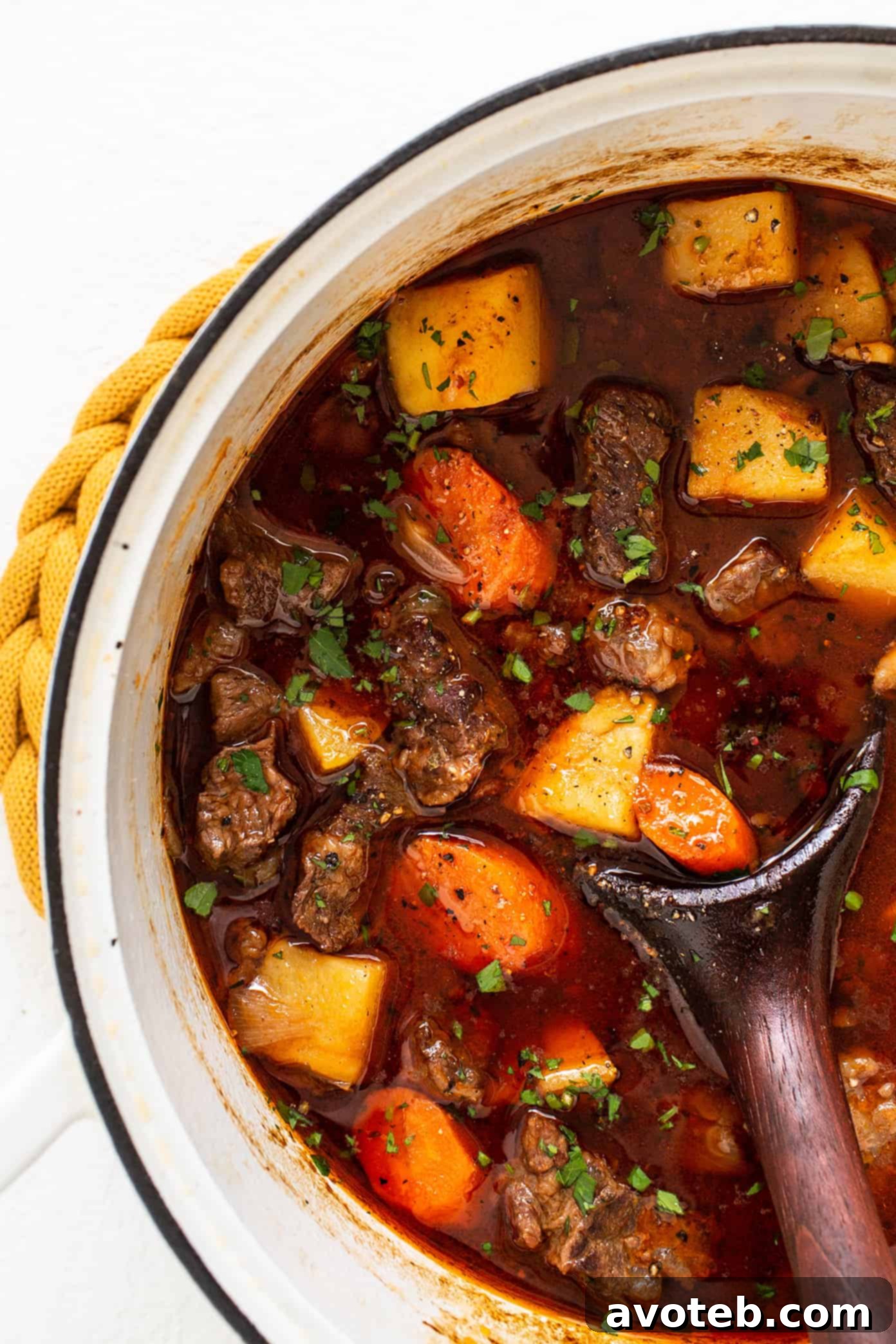 A steaming bowl of Guinness Beef Stew, garnished with fresh parsley, showcasing tender beef, potatoes, and carrots in a rich, dark broth. Perfect comfort food.