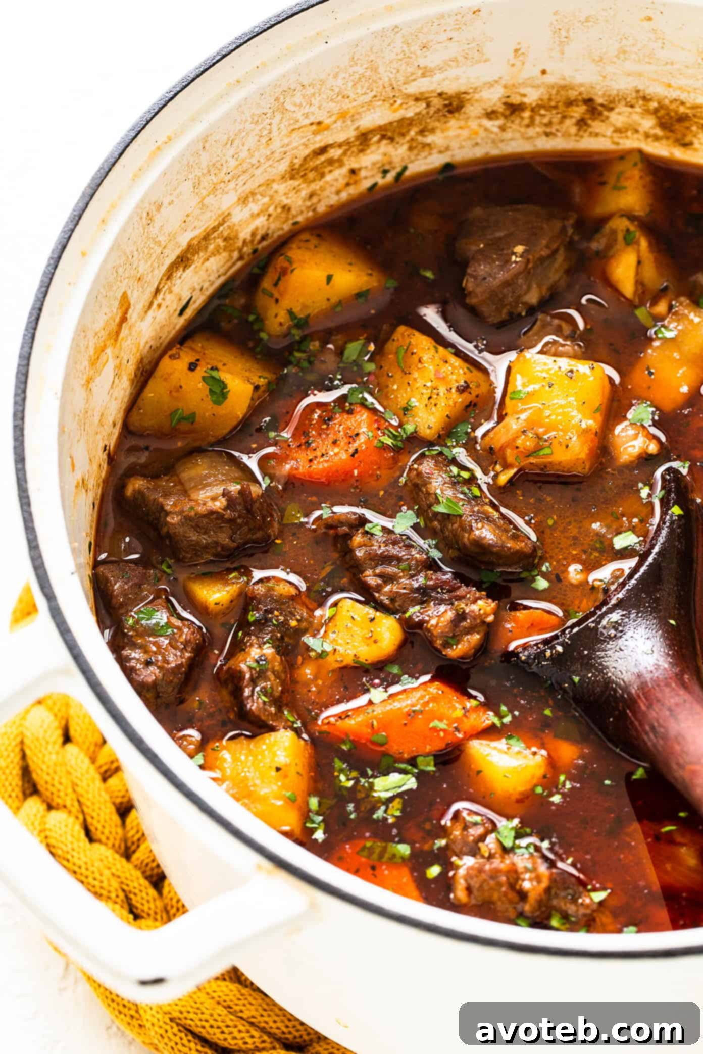 Guinness Beef Stew simmering in a large pot on the stovetop, showing the rich texture of the broth and ingredients.