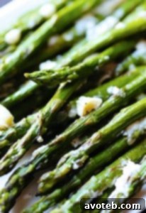 Blue Cheese Roasted Asparagus with melted cheese and fresh herbs, presented as a gourmet side dish.