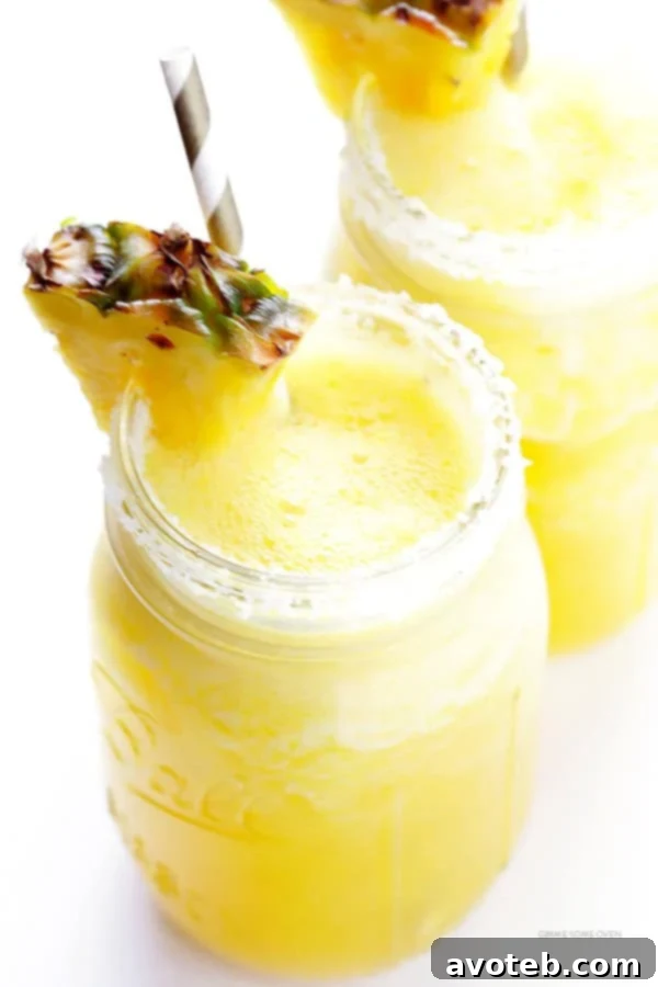 A hand pouring a blended mixture of pineapple and lime into a glass with ice, illustrating the preparation step for Fresh Pineapple Margaritas.