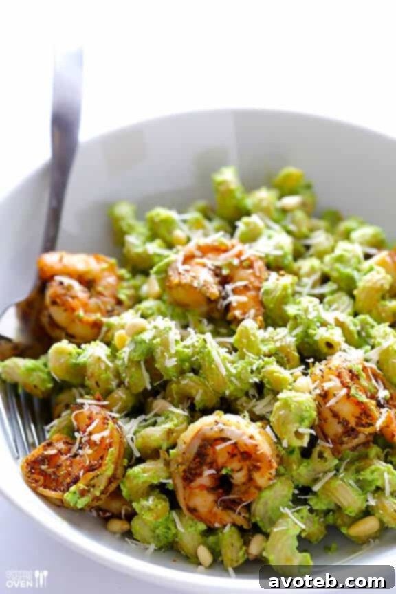 A bowl of asparagus-spinach pesto pasta with blackened shrimp and a glass of wine.