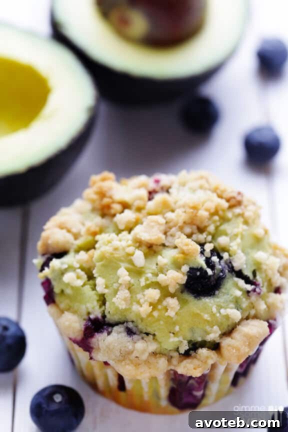 Two blueberry avocado muffins cut in half to reveal the moist, fluffy crumb and distribution of blueberries, with a subtle green tint.