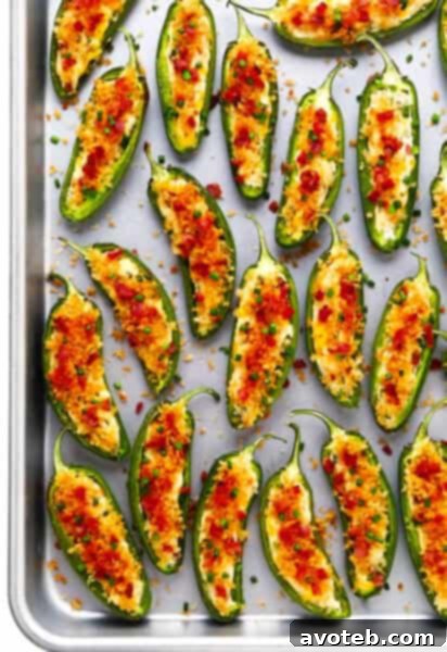 Tray of golden baked jalapeno poppers garnished with bacon and chives