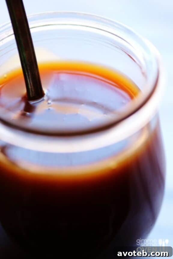 Glass jar of homemade Microwave Caramel Sauce with a spoon.