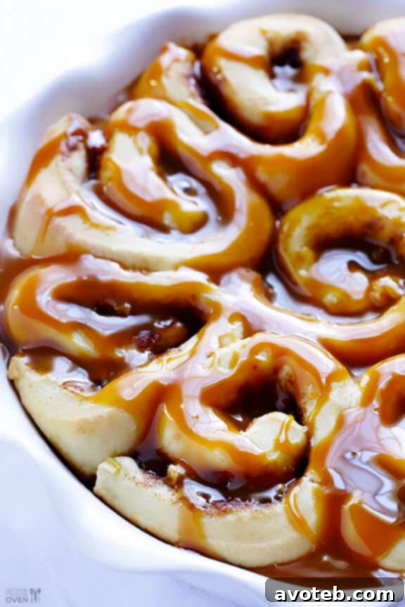 Close-up of baked caramel apple cinnamon rolls with a golden-brown top.