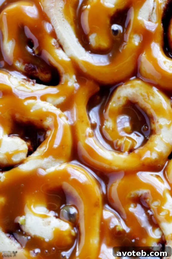 A serving of warm caramel apple cinnamon rolls on a plate, showcasing the gooey center and drizzle.