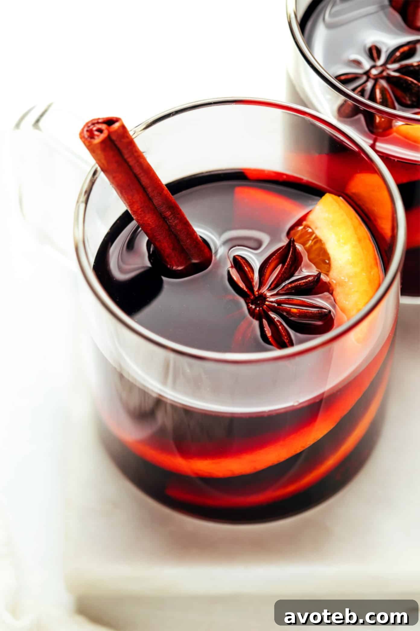 A steaming mug of homemade mulled wine garnished with an orange slice and cinnamon stick, evoking warmth and festive cheer.