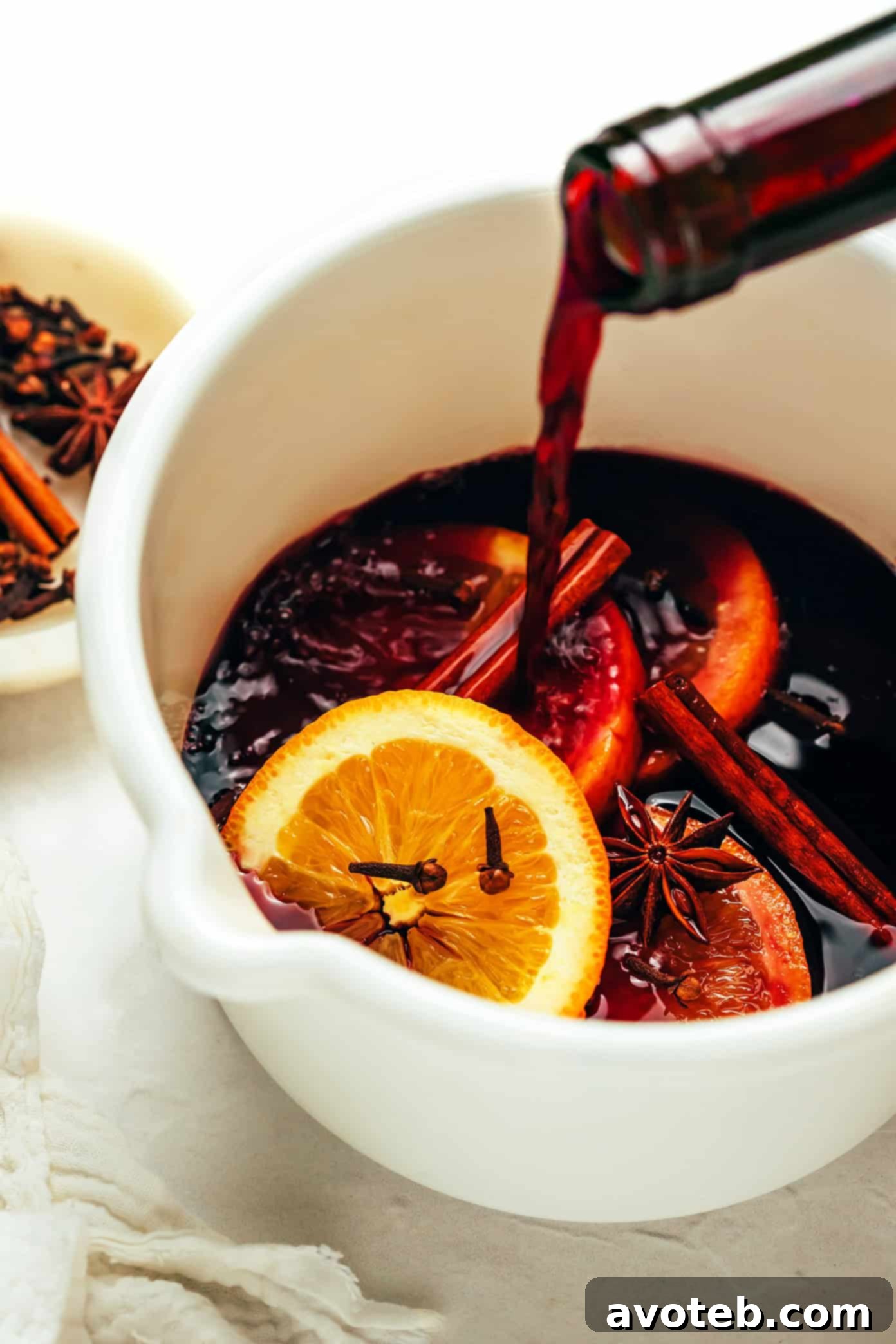 Steps for making mulled wine: a hand stirring ingredients in a saucepan, followed by the simmering process.