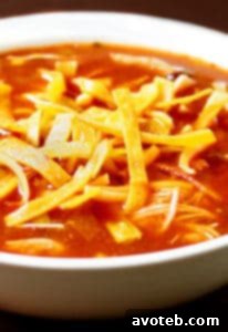 A bowl of Slow-Cooker Chicken Tortilla Soup garnished with fresh cilantro and lime.