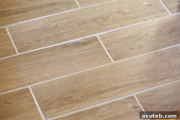Newly installed kitchen flooring, a beautiful light-colored tile, replacing old industrial tiles.