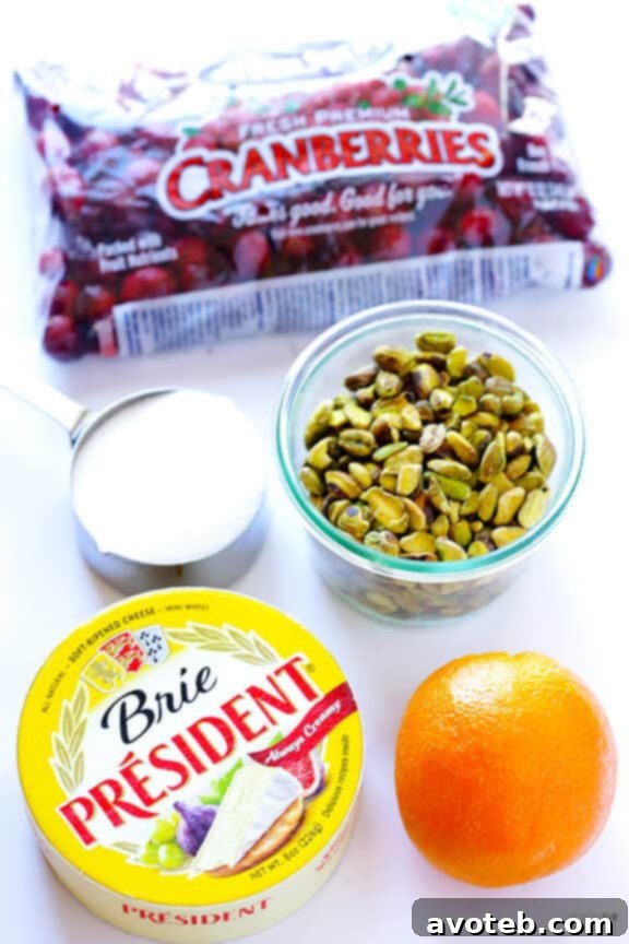 Cranberry Pistachio Baked Brie Recipe Ingredients for Cranberry Pistachio Baked Brie displayed on a wooden surface.