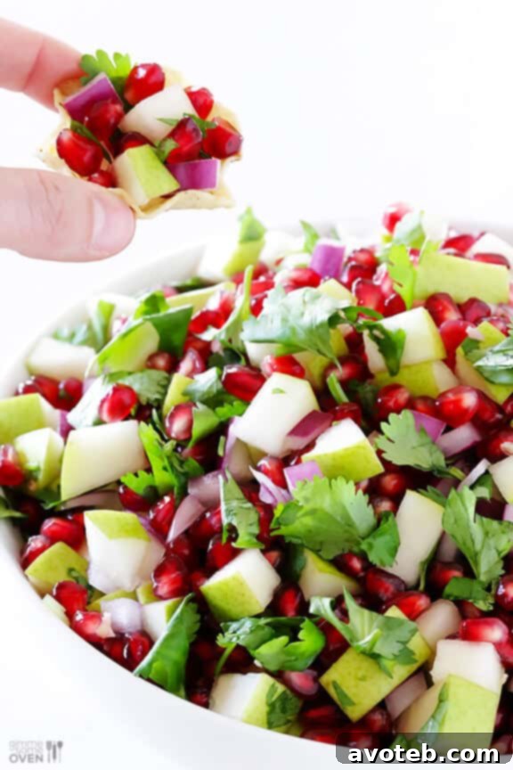 A vibrant bowl of 5-Ingredient Pear Pomegranate Salsa, showcasing fresh pears, ruby red pomegranate seeds, green cilantro, and red onion, ready to be enjoyed.