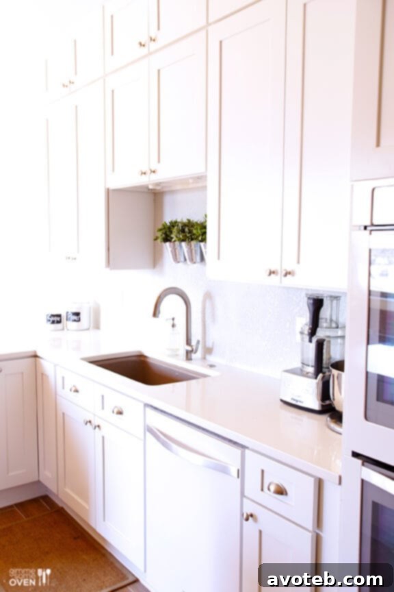 Spacious white kitchen with modern design, featuring large island and pristine surfaces
