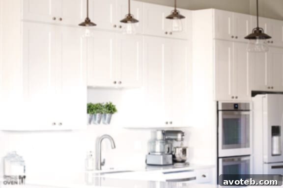 Stylish kitchen lighting fixtures illuminate the elegant white interior