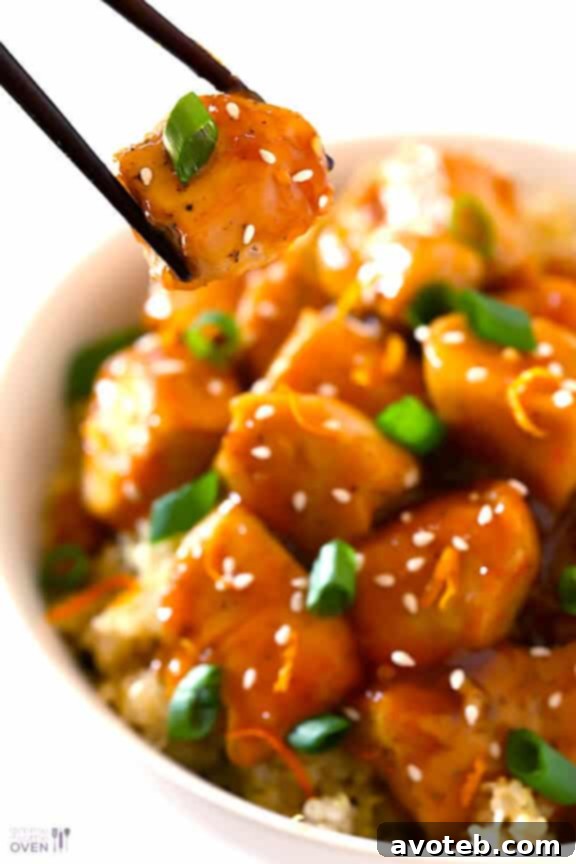 Skinny Orange Chicken Recipe | gimmesomeoven.com #newyears #chicken #recipe Close-up of a single serving of Skinny Orange Chicken with a fork, emphasizing its tender texture and glossy sauce.