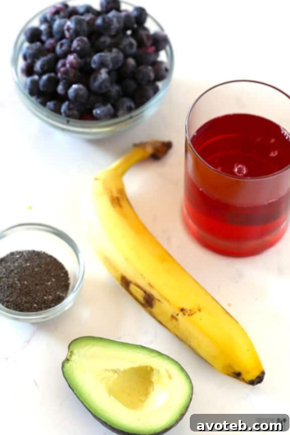 Fresh ingredients for the Brain Power Smoothie laid out: blueberries, avocado, banana, chia seeds, and pomegranate juice, ready for blending.