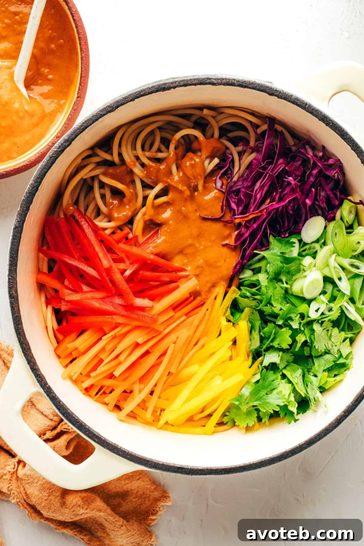 This rainbow peanut noodles recipe is made with colorful fresh veggies, your choice of noodles, and the most irresistible sesame-lime peanut sauce. Feel free to add in a protein (chicken, shrimp, beef, tofu, etc), serve warm or cold, and use whatever colorful vegetables you have on hand. Perfect for easy meal prep too! | gimmesomeoven.com Mixing Rainbow Peanut Noodles with vegetables and sauce
