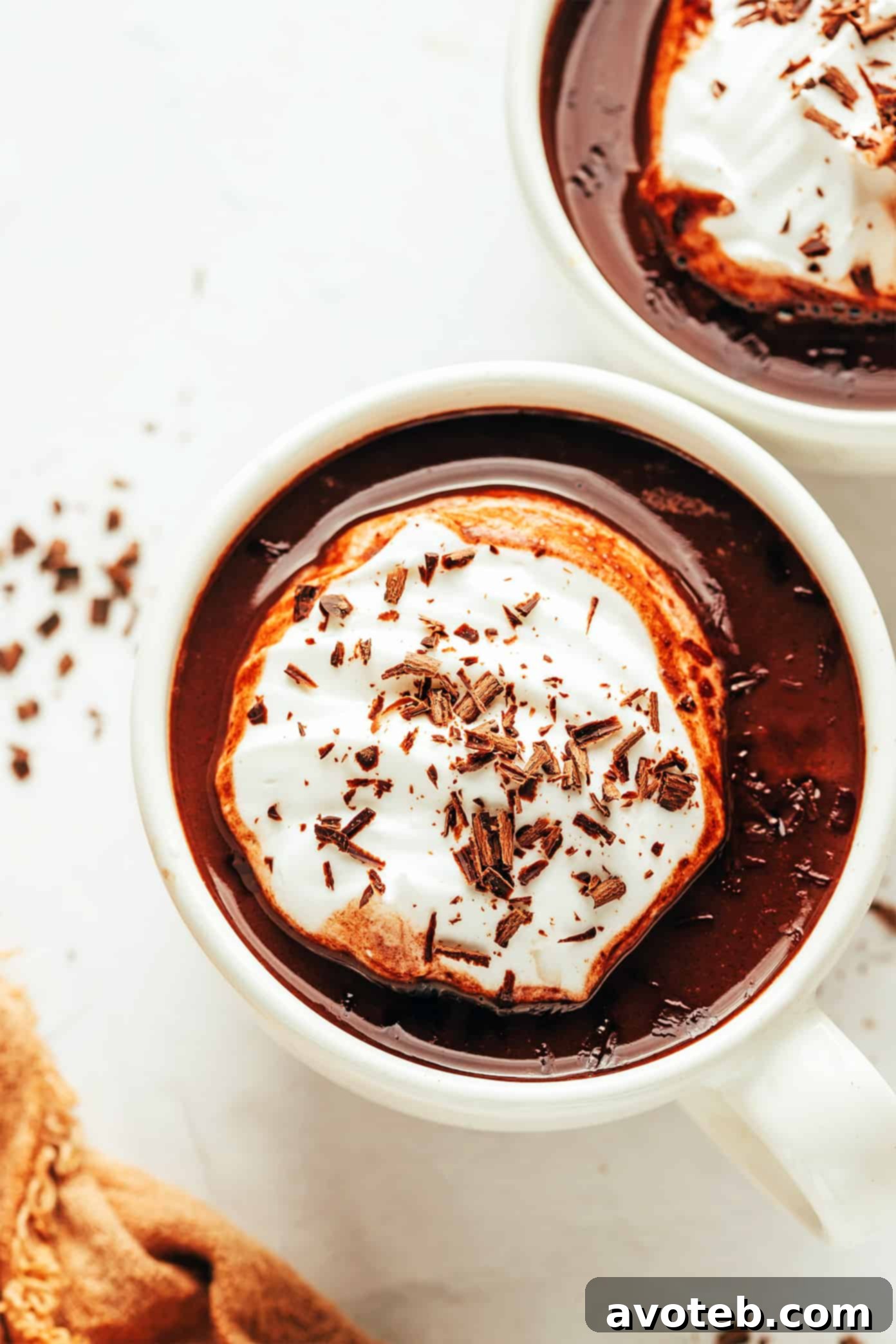 Velvet Cocoa 6 A hand holding a mug of hot chocolate with a variety of toppings visible in the background.