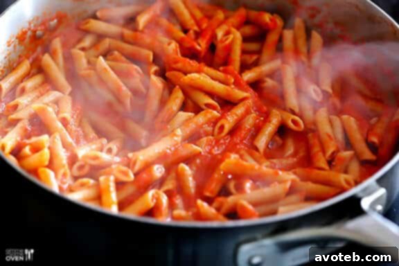 Pasta being tossed with the red pepper sauce.