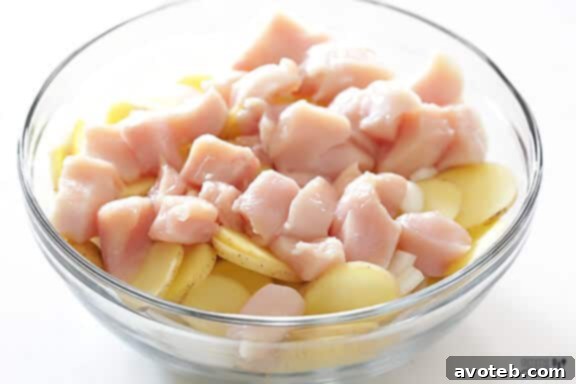 Adding chicken pieces to the mixing bowl with vegetables