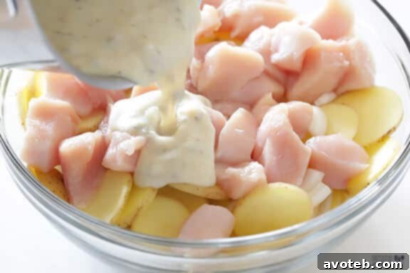 Pouring creamy soup mixture over chicken and potatoes