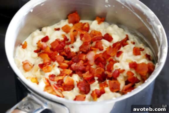 Stirring in crispy bacon to blue cheese macaroni and cheese.