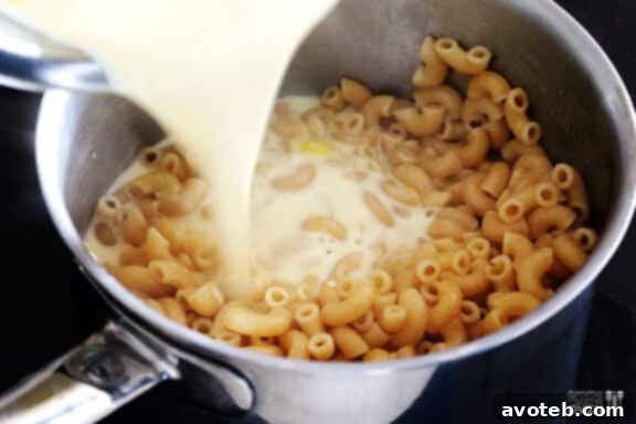 Pouring creamy sauce over cooked macaroni.