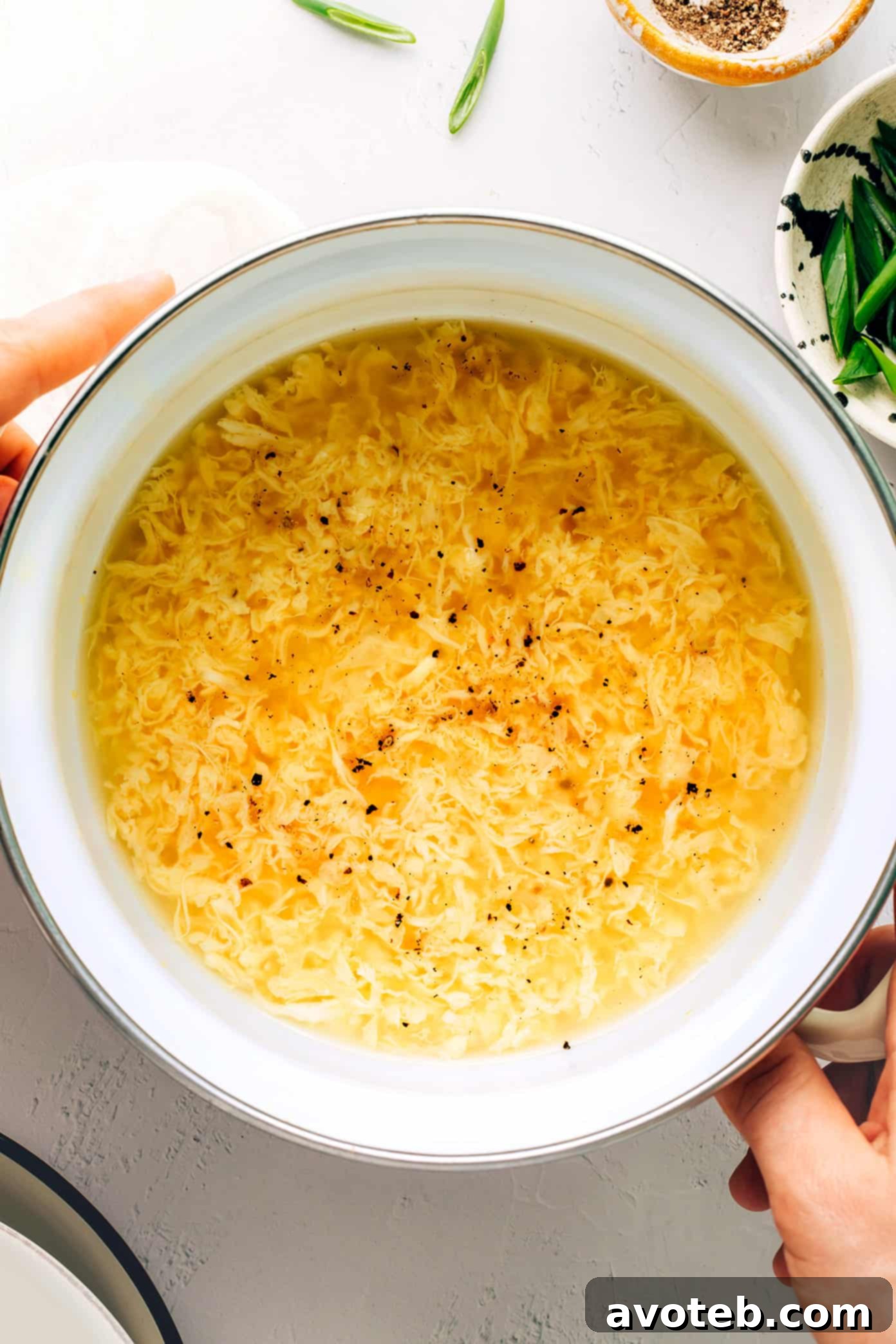 Six different bowls of comforting soups, including egg drop soup, miso soup, and tom kha gai, arranged on a table.