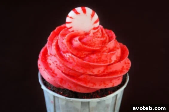 A beautifully frosted Peppermint Mocha Cupcake, adorned with festive sprinkles and a candy cane piece, ready to be enjoyed.