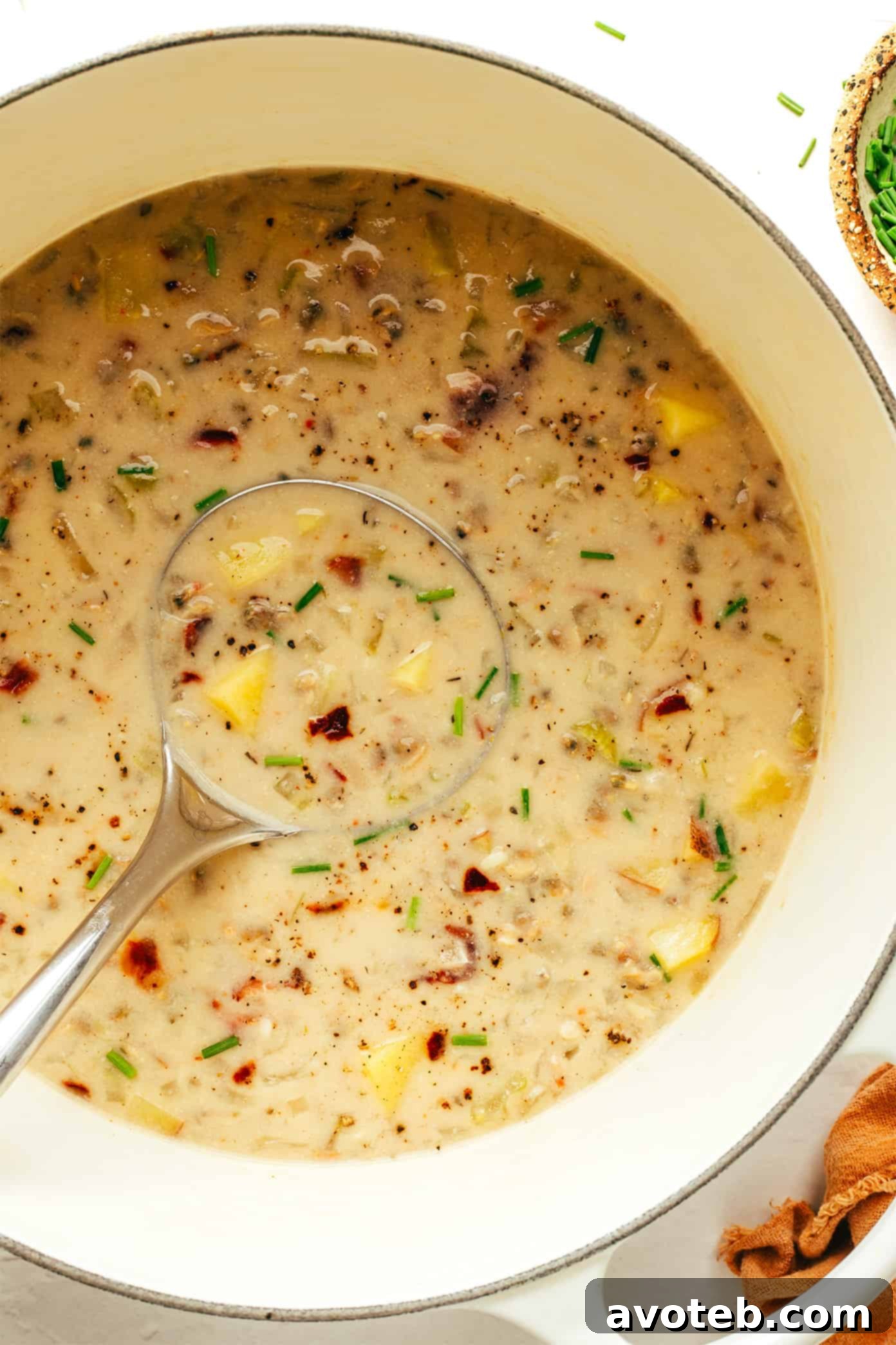 A bowl of creamy New England Clam Chowder garnished with fresh herbs and a side of oyster crackers.