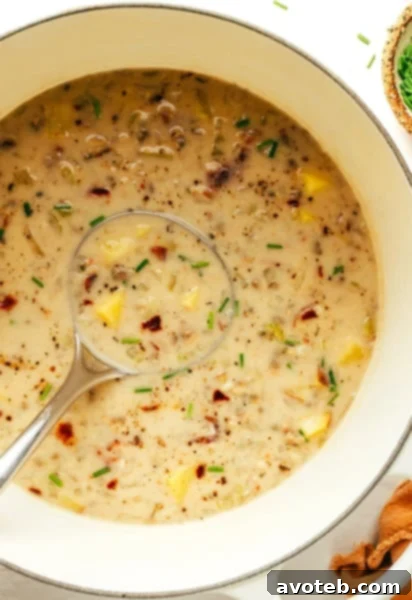 A bowl of creamy New England Clam Chowder garnished with fresh herbs and a side of oyster crackers.
