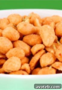 A close-up of crunchy spicy rosemary peanuts in a bowl, showing the herb and spice coating.