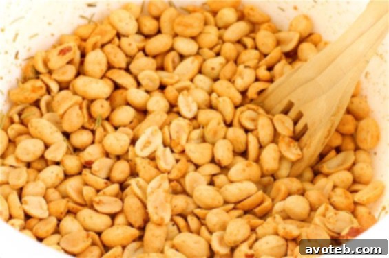 A beautiful wooden bowl filled with freshly made spicy rosemary peanuts, garnished with fresh rosemary sprigs.
