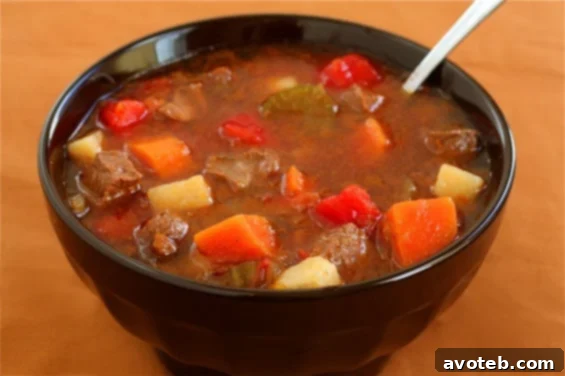 A steaming bowl of homemade Steak Soup (Vegetable Beef Soup) garnished with fresh parsley.
