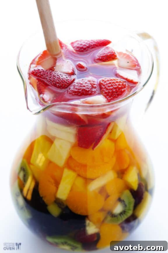 A single glass of Easy Rainbow Sangria, showcasing the vibrant fruit layers against a white background.