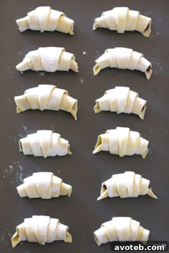 Rolling Nutella-filled puff pastry into a croissant shape