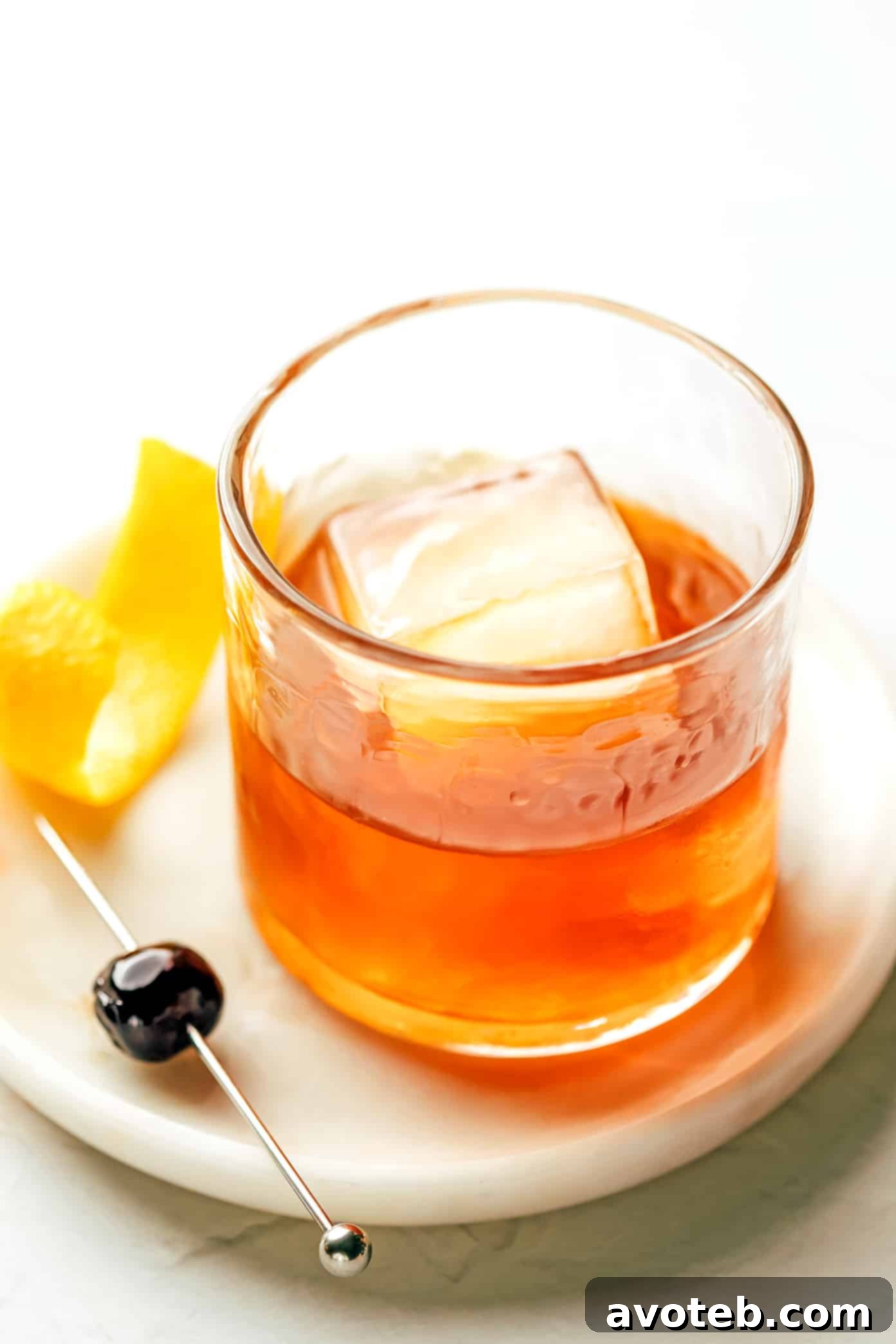 The classic Old Fashioned cocktail: simple, satisfying, and sophisticated. A finished Old Fashioned cocktail with a Luxardo cherry and an orange peel, ready for drinking.